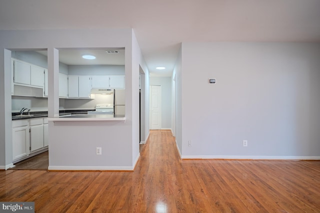 kitchen with white cabinets, light hardwood / wood-style floors, and white appliances