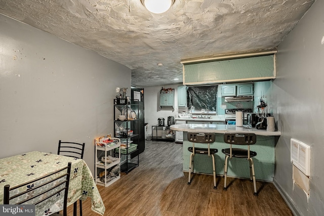 kitchen featuring dark wood-type flooring, stainless steel range with electric stovetop, a kitchen breakfast bar, green cabinetry, and kitchen peninsula