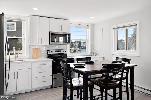 kitchen featuring white cabinets, light wood-type flooring, stainless steel appliances, and sink