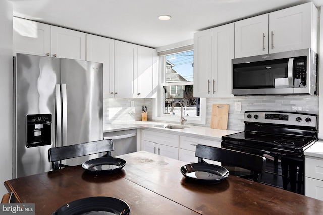 kitchen with appliances with stainless steel finishes, backsplash, white cabinetry, and sink