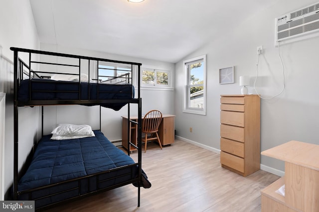 bedroom featuring a wall mounted AC, hardwood / wood-style floors, vaulted ceiling, and a baseboard heating unit