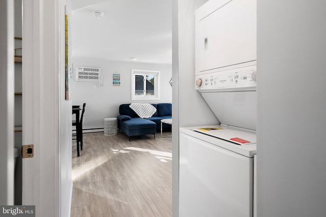 clothes washing area featuring a wall mounted AC, a baseboard radiator, light hardwood / wood-style floors, and stacked washer / drying machine