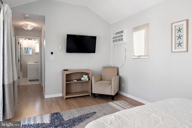 bedroom with hardwood / wood-style floors, ensuite bath, lofted ceiling, and a wall mounted AC