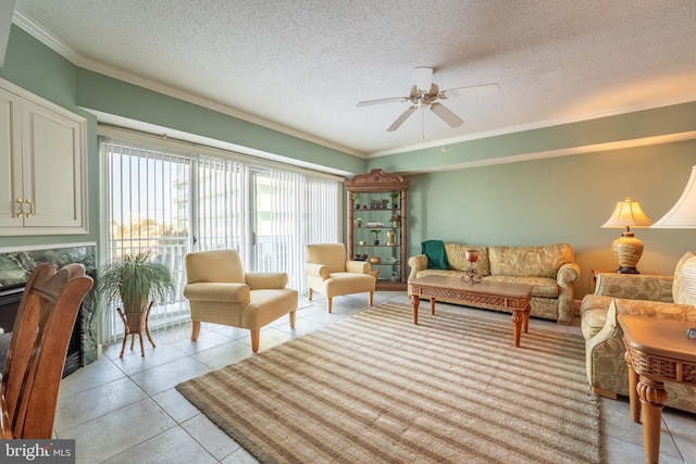 tiled living room featuring ceiling fan, a textured ceiling, and ornamental molding