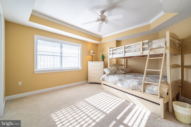 bedroom with ceiling fan, carpet floors, crown molding, and a tray ceiling