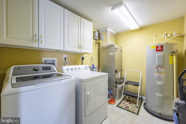 washroom featuring cabinets, light tile patterned floors, washing machine and dryer, and water heater