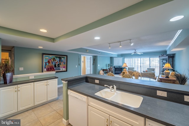 kitchen featuring dishwasher, sink, ceiling fan, a tray ceiling, and white cabinetry