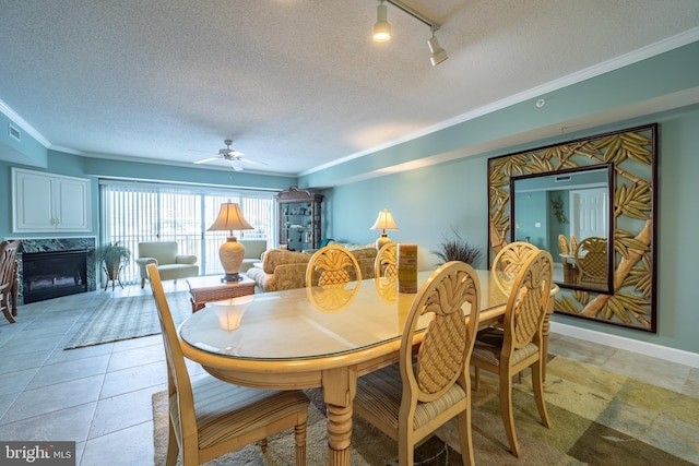 dining room with ceiling fan, a high end fireplace, a textured ceiling, and ornamental molding