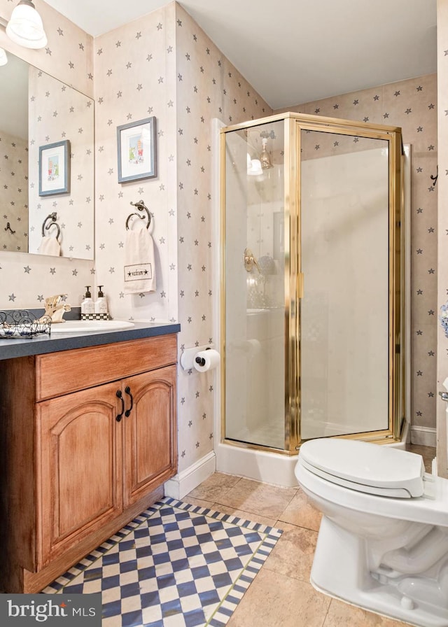 bathroom featuring tile patterned floors, vanity, toilet, and a shower with shower door