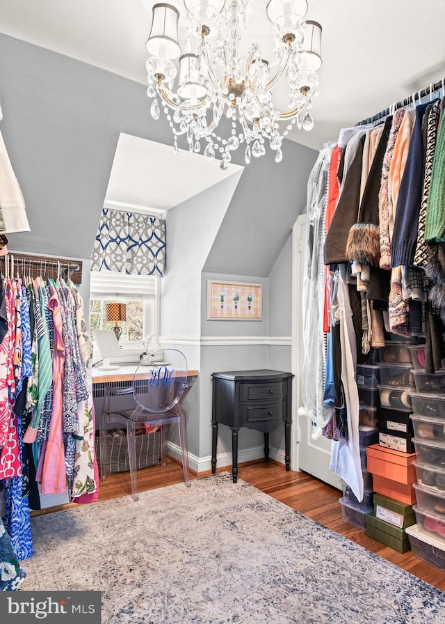 spacious closet featuring wood-type flooring, a chandelier, and vaulted ceiling