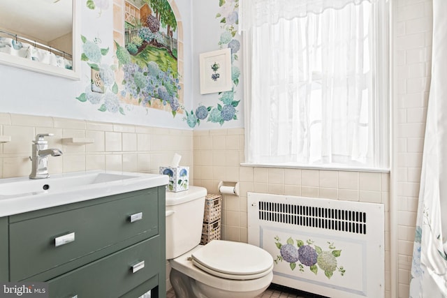 bathroom featuring vanity, radiator, tile walls, and toilet