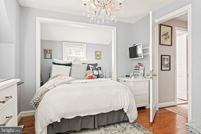 bedroom with an inviting chandelier and dark hardwood / wood-style flooring