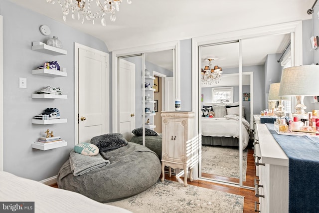 bedroom featuring a notable chandelier, two closets, and hardwood / wood-style floors