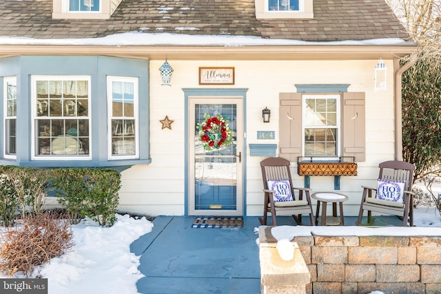 snow covered property entrance with covered porch