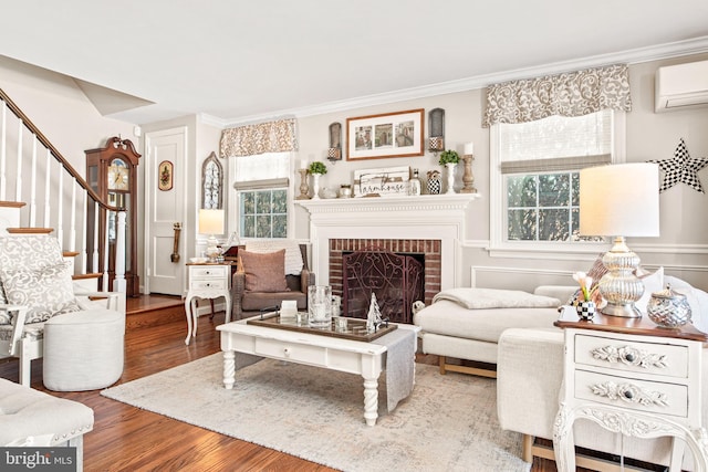 living room with a wall mounted AC, a brick fireplace, wood-type flooring, and a wealth of natural light