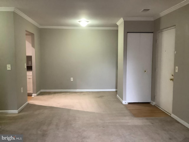 empty room featuring crown molding and light colored carpet