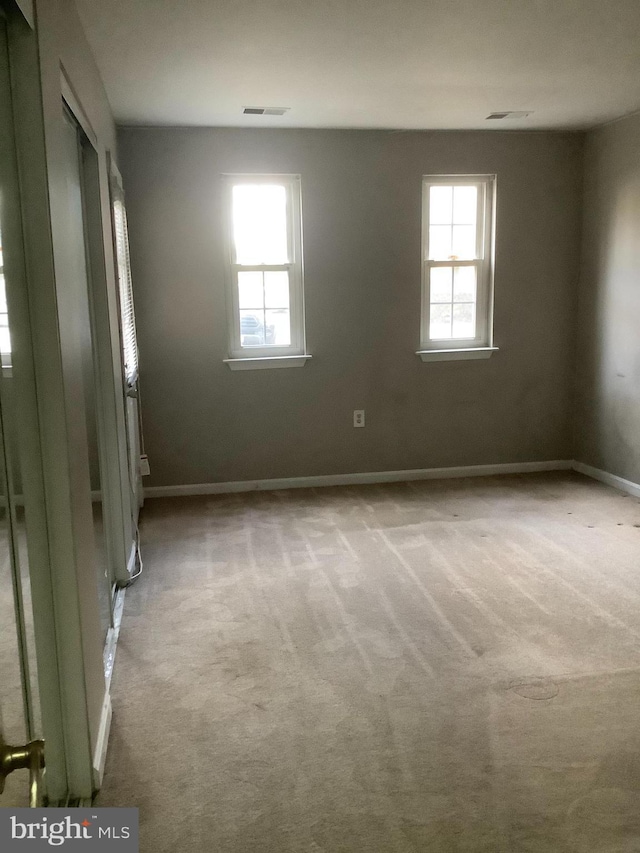 unfurnished room featuring light colored carpet and a healthy amount of sunlight