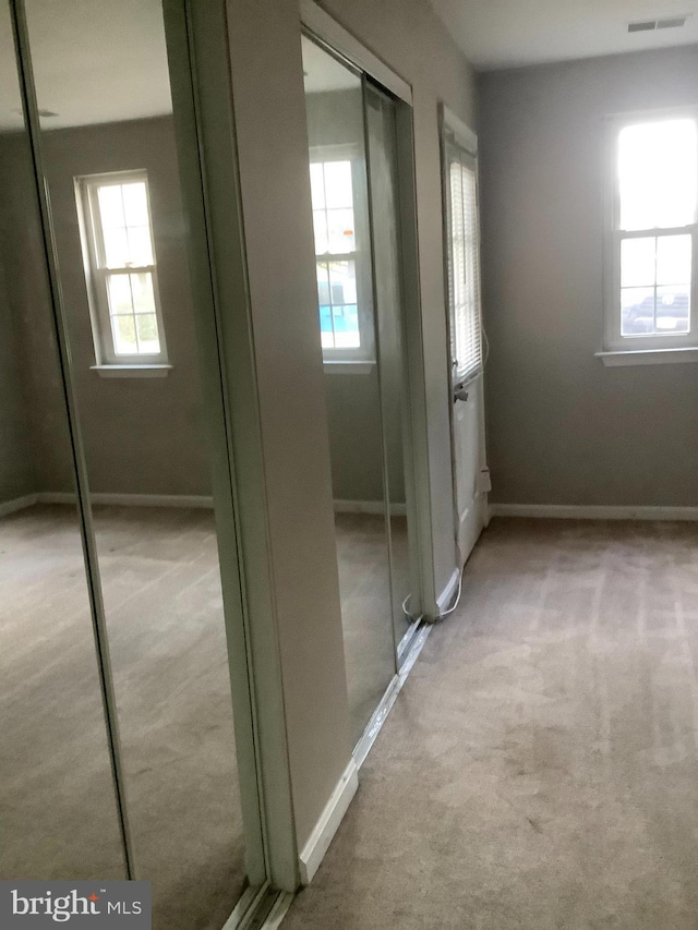 hallway with plenty of natural light and light carpet