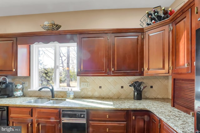 kitchen featuring tasteful backsplash, light stone countertops, and sink