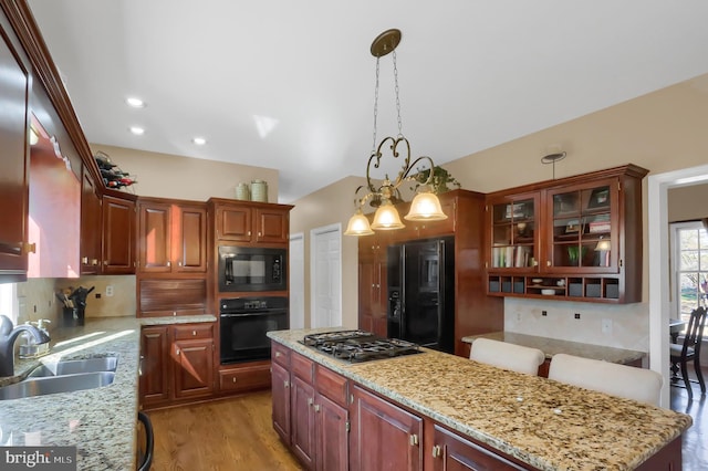 kitchen with sink, black appliances, hanging light fixtures, and light stone countertops