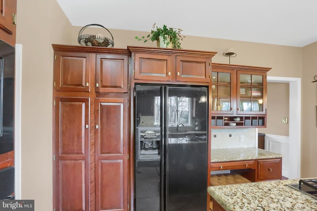 kitchen with black refrigerator with ice dispenser and light stone countertops