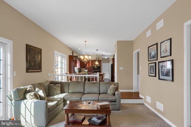 carpeted living room with a chandelier