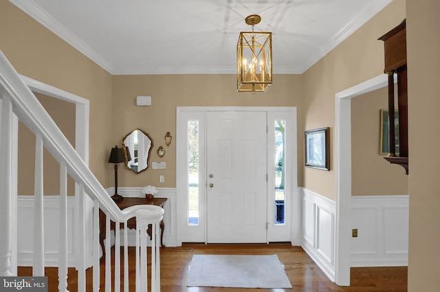 entryway with ornamental molding, wood-type flooring, and a chandelier