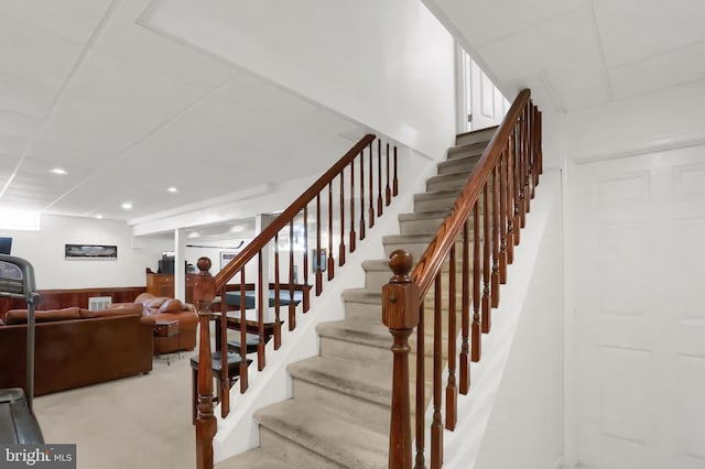 staircase featuring a drop ceiling and wooden walls