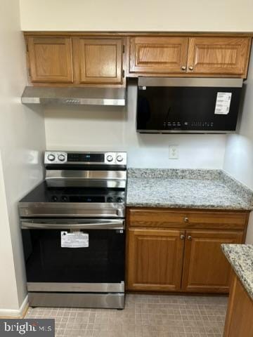 kitchen featuring light stone countertops and electric range