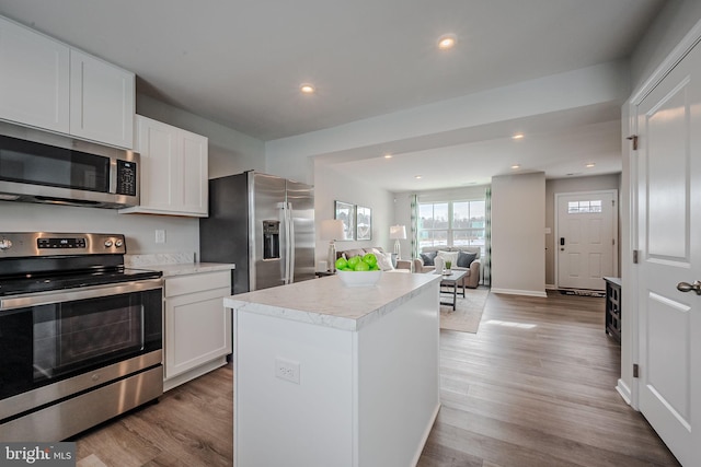 kitchen with a kitchen island, stainless steel appliances, light hardwood / wood-style floors, and white cabinets