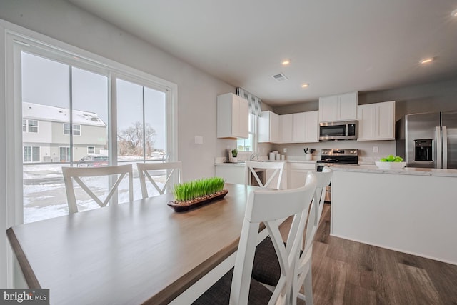 kitchen with appliances with stainless steel finishes, dark hardwood / wood-style floors, and white cabinetry