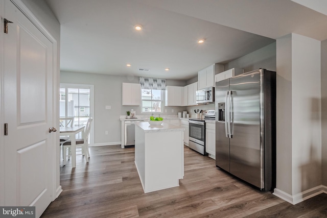 kitchen featuring a kitchen island, white cabinets, light hardwood / wood-style floors, and appliances with stainless steel finishes