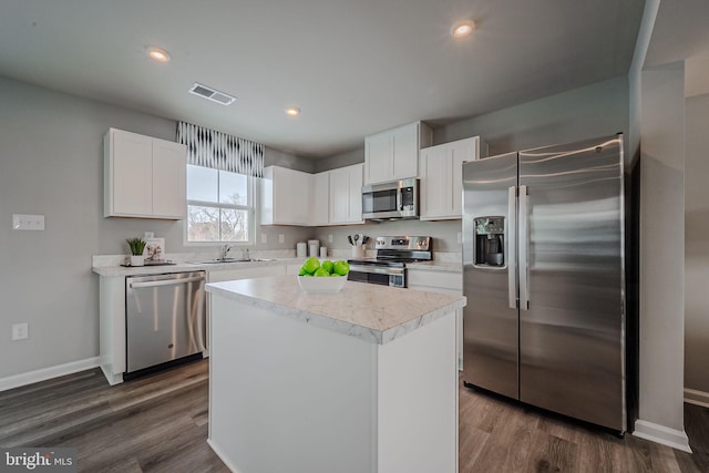 kitchen featuring appliances with stainless steel finishes, white cabinets, sink, and a kitchen island