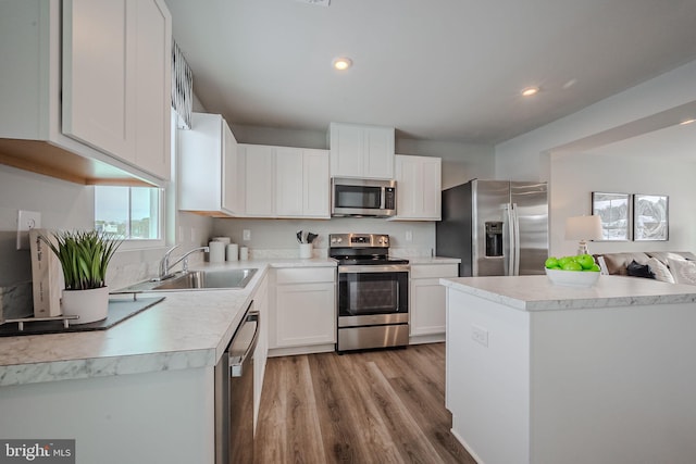 kitchen with white cabinets, appliances with stainless steel finishes, light hardwood / wood-style flooring, and sink