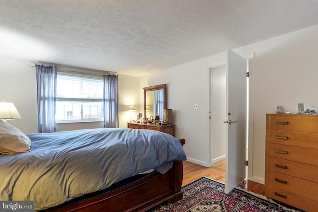 bedroom with a textured ceiling and light hardwood / wood-style floors