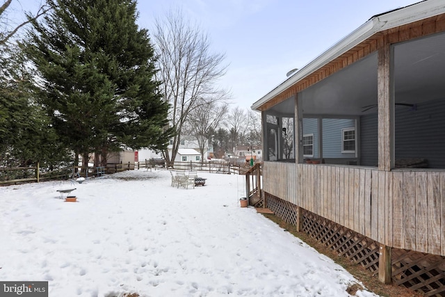 yard covered in snow featuring a sunroom