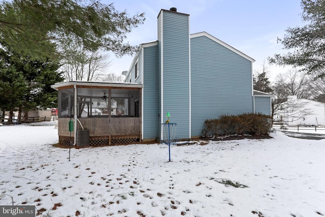 view of snow covered exterior with ceiling fan and a sunroom