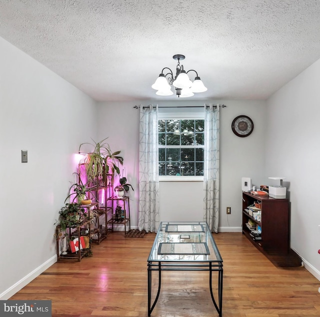 dining area with a textured ceiling, hardwood / wood-style floors, and a notable chandelier