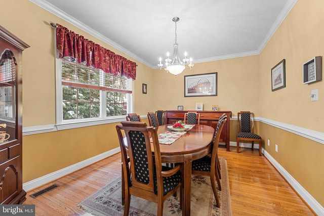 dining room featuring light wood-type flooring, a chandelier, and crown molding