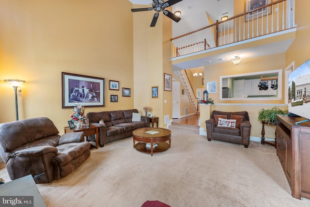 living room with light carpet, a towering ceiling, and ceiling fan with notable chandelier