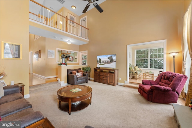 living room featuring carpet, ceiling fan, and a towering ceiling