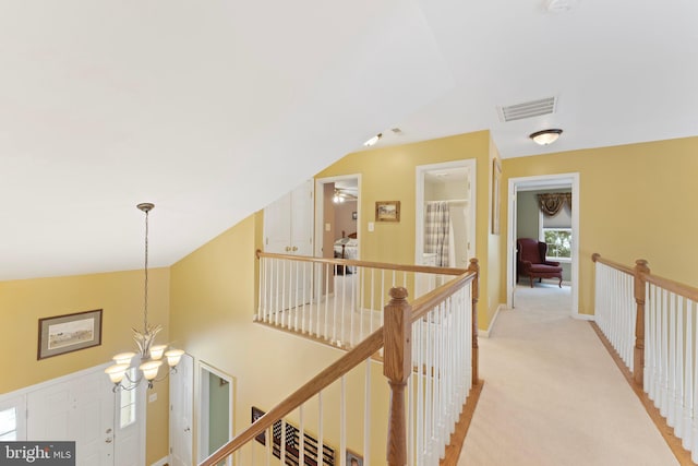 corridor with vaulted ceiling, light carpet, and an inviting chandelier