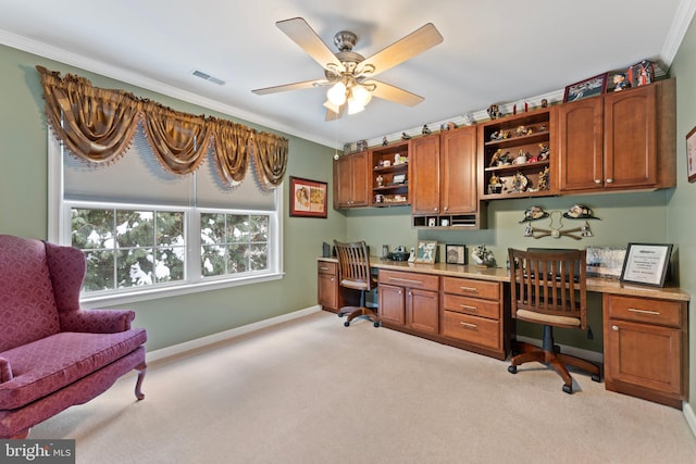 carpeted office with ceiling fan, crown molding, and built in desk