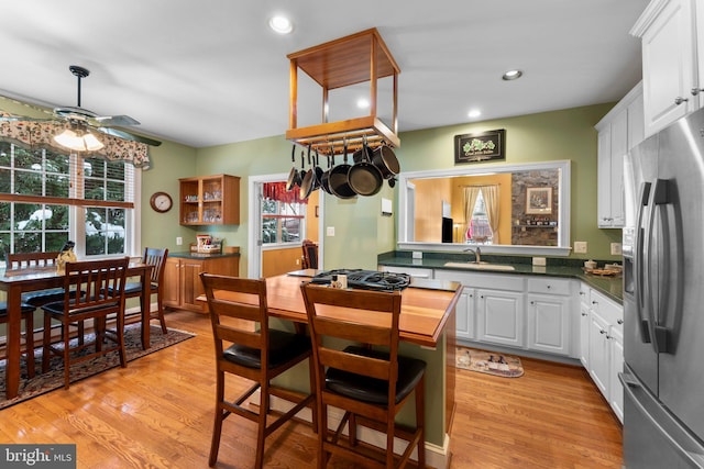 kitchen with light hardwood / wood-style floors, ceiling fan, stainless steel appliances, white cabinets, and sink