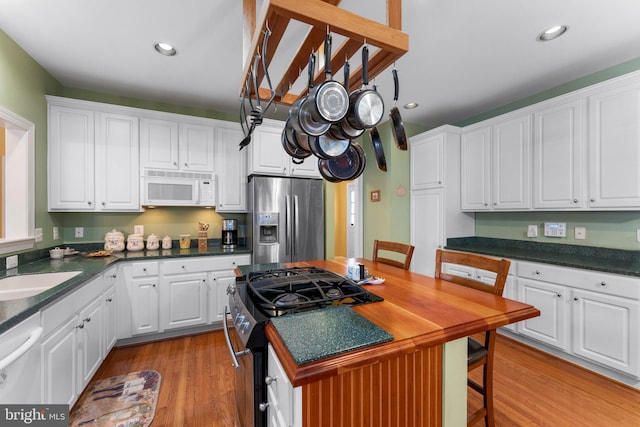 kitchen featuring light wood-type flooring, appliances with stainless steel finishes, sink, and white cabinetry