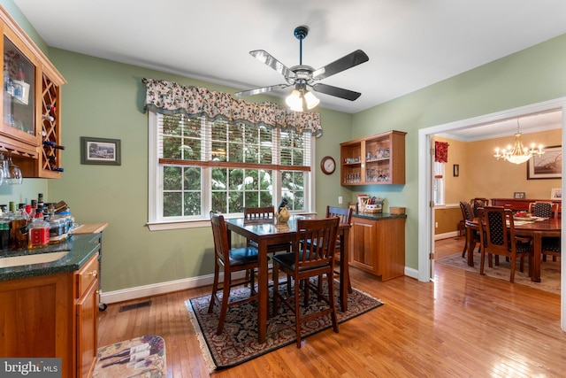 dining space featuring light hardwood / wood-style floors, crown molding, and ceiling fan with notable chandelier