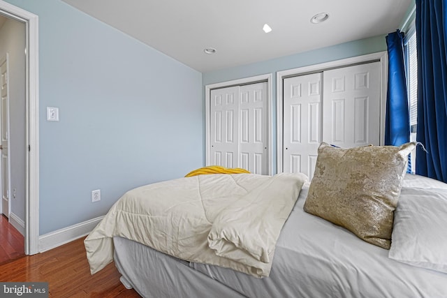 bedroom with dark hardwood / wood-style flooring and two closets