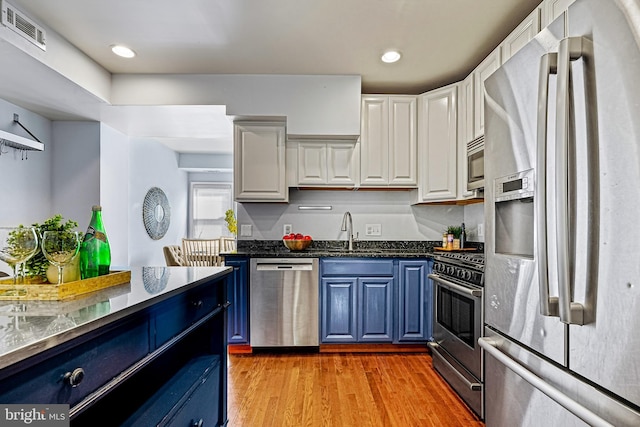 kitchen featuring appliances with stainless steel finishes, white cabinets, light hardwood / wood-style flooring, blue cabinets, and sink