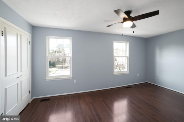 spare room with plenty of natural light, ceiling fan, and dark hardwood / wood-style flooring