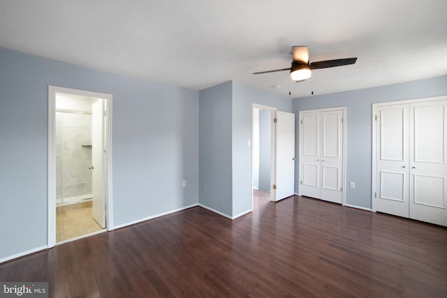 unfurnished bedroom with two closets, dark hardwood / wood-style floors, ensuite bath, and ceiling fan